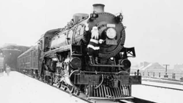 Train à vapeur des années 1940 avec un père Noël grimpé dessus.