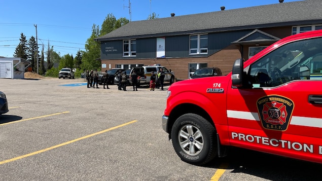 Des secouristes de la Sûreté du Québec près d'un édifice municipal en été. 