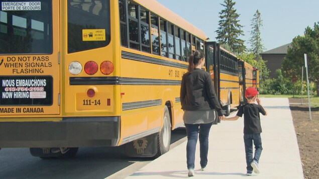 Une mère et son enfant vont prendre l'autobus scolaire. Une mère et son enfant vont prendre l'autobus scolaire.