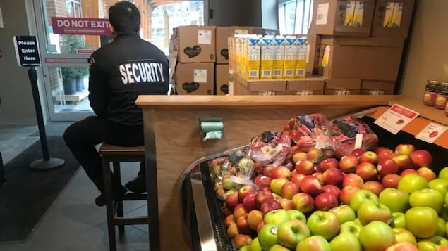 Un homme assis sur un tabouret à l'intérieur d'un supermarché.