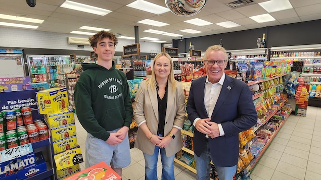 Trois personnes dans un dépanneur qui sourient à la caméra.