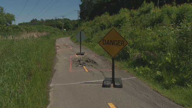 Une piste cyclable endommagée avec une pancarte avec la mention « Danger ». Une piste cyclable endommagée avec une pancarte avec la mention « Danger ».