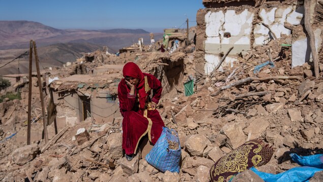 امرأة جالسة وسط الأنقاض في قريتها دوزرو، في المغرب، التي دمّرها الزلزال بشكل شبه كلي. 