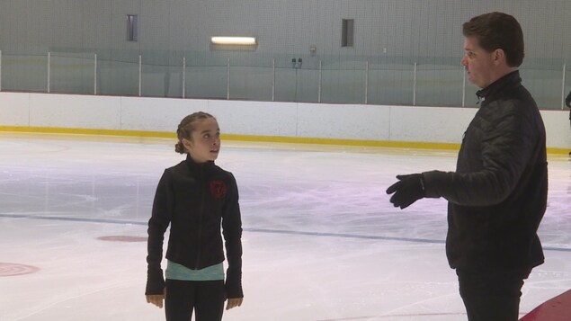 Un homme enseigne le patinage artistique à une jeune fille