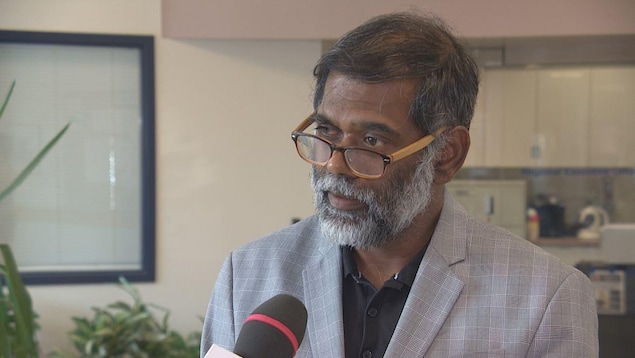 Senthil Damodharan porte une blouse blanche et des lunettes brunes. Il a la peau matte et la barbe grisonnante. Senthil Damodharan porte une blouse blanche et des lunettes brunes. Il a la peau matte et la barbe grisonnante.