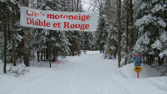 Un sentier enneigé au-dessus duquel est accrochée une banderole du club.