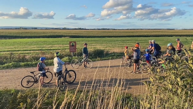 Un guide à vélo explique quelque chose à un groupe de gens à vélo lors d'une pause le long du chemin, sur un sentier.
