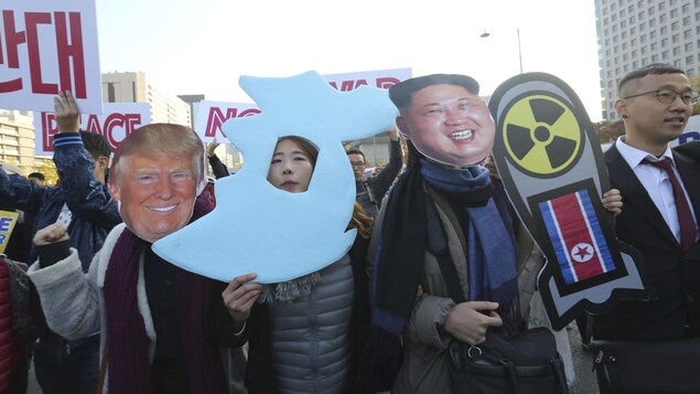 Des manifestants tiennent des affiches qui se moquent de Donald Trump et Kim Jong-un. Des manifestants tiennent des affiches qui se moquent de Donald Trump et Kim Jong-un.