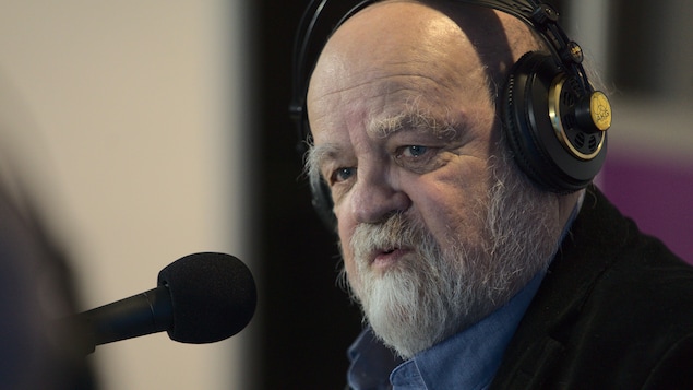 Gros plan de Serge Bouchard devant le micro, avec des écouteurs.