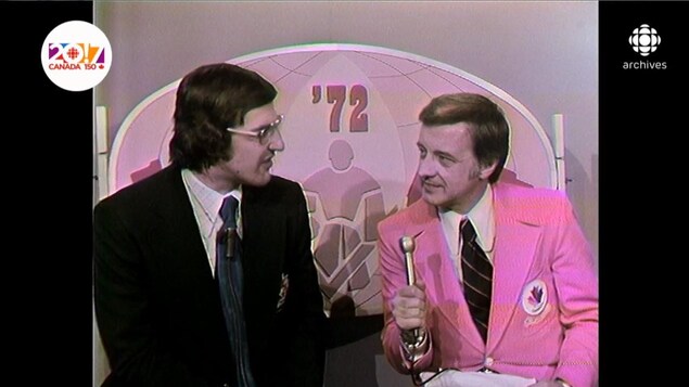 Guy Ferron, tenant le micro aux côtés de Serge Savard, dans le décor de l'émission de la Série du Siècle de 1972