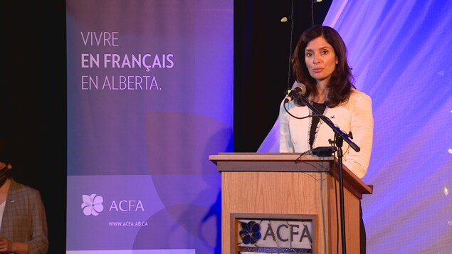 Une femme devant un micro sur une scène dans la Cité francophone d'Edmonton.
