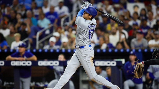 Un joueur de baseball termine son élan au bâton. 