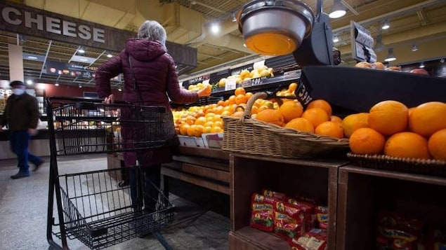 A woman picking fruit in grocery store.
