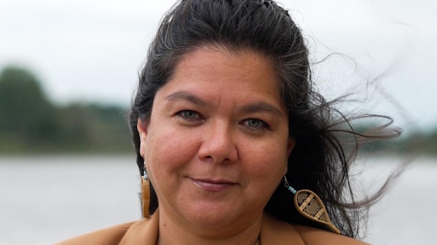 Shushan Bacon devant la caméra, avec une étendue d'eau à l'arrière-plan.