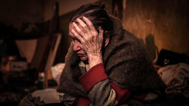 Une femme, Klaudia Pushnir, 88 ans, se prend la tête dans les mains, en pleurant, dans un sous-sol. 
