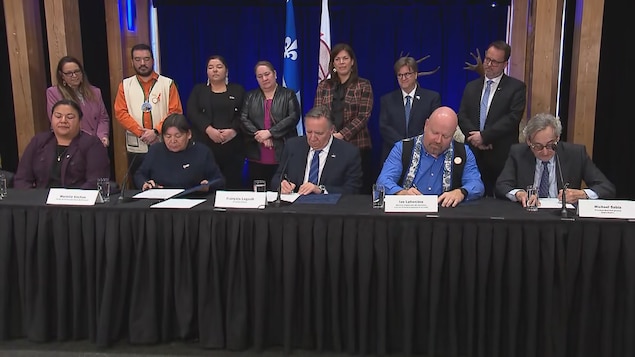 Government representatives and the Innu community of Besamite sign the treaty. 