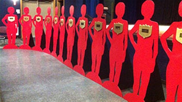 Exposition d'une douzaine de silhouettes en bois portant le nom de victimes.