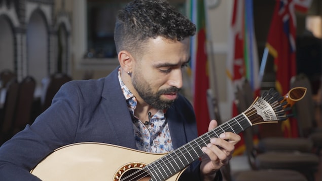 Simon Arruda qui tient sa guitare dans une salle de répétition à Toronto.