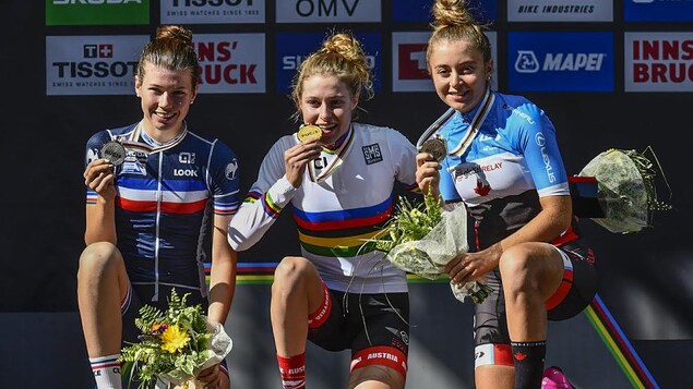 Simone Boilard (à droite) est souriante sur le podium et montre sa médaille. Simone Boilard (à droite) est souriante sur le podium et montre sa médaille.