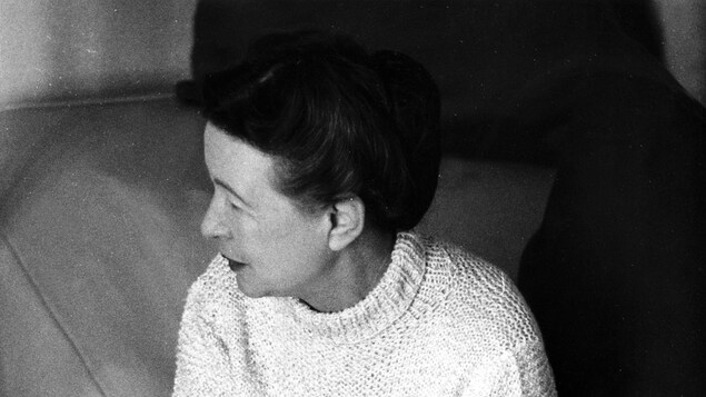 Simone de Beauvoir, assise sur un canapé.