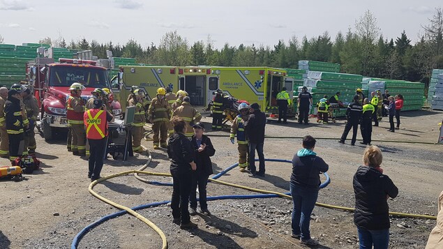 Des dizaines de pompiers déploient leurs boyaux d'arrosage, s'occupent de blessés et discutent, à proximité de leurs camions et d'ambulances. Des dizaines de pompiers déploient leurs boyaux d'arrosage, s'occupent de blessés et discutent, à proximité de leurs camions et d'ambulances.