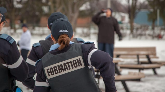 Dans une simulation, trois futurs policiers en formation s'apprêtent à intervenir auprès d'une personne qui boit dans un lieu public.