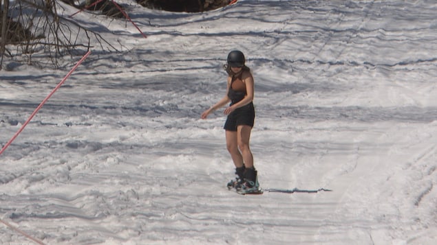 Une planchiste dévale une piste en short et en manches courtes. 