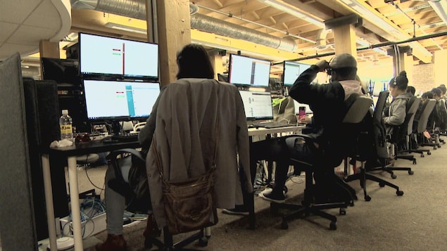 Des employés font face à des écrans d'ordinateurs. Des employés font face à des écrans d'ordinateurs.