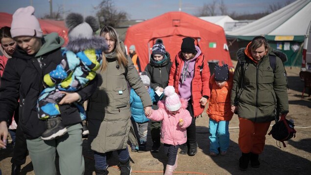 Des réfugiés marchent près de tentes de la Croix-Rouge internationale.