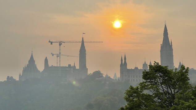 Une vue lointaine du Parlement enveloppé dans un épais smog. Lueur jaunâtre du soleil.