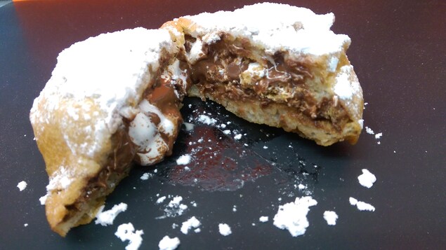 S'more frit saupoudré de sucre glace, coupé en deux, laissant couler du chocolat et du marshmallow. S'more frit saupoudré de sucre glace, coupé en deux, laissant couler du chocolat et du marshmallow.
