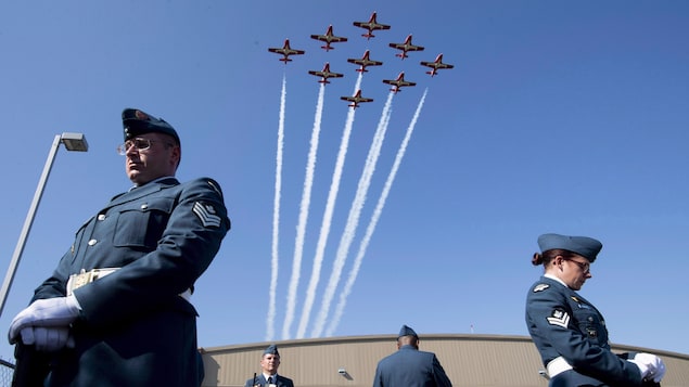 Des avions volent au-dessus des têtes de nombreux militaires.