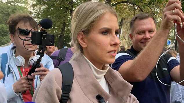 Lioubov Sobol marche dans une rue bondée, entourée de photographes et de reporters.