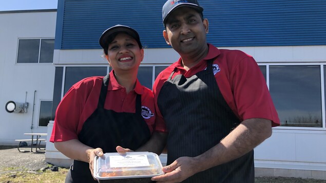 Le couple souriant devant les locaux de leur entreprise tiennent dans leur main un plat de morue au beurre pour emporter.