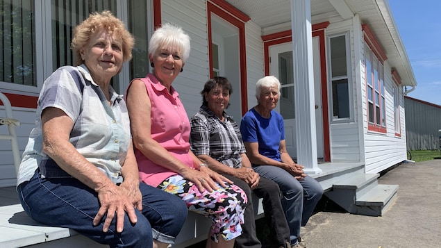Quatre femmes assises sur le balcon d'une maison ancestrale l'été.