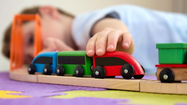 Un enfant joue avec son train jouet sur le plancher