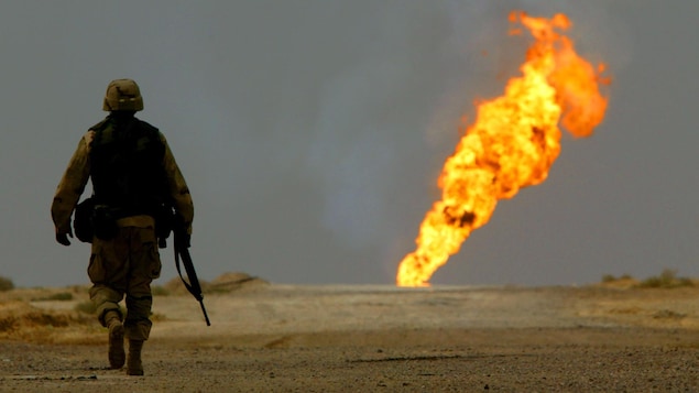 Un soldat américain marche en solitaire vers un puits de pétrole qui brûle.