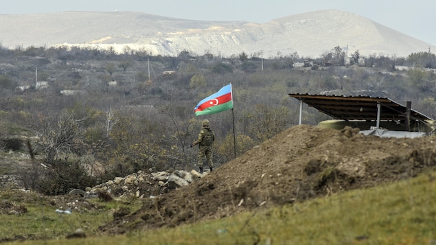 Un soldat azerbaïdjanais près d'un drapeau de son pays.