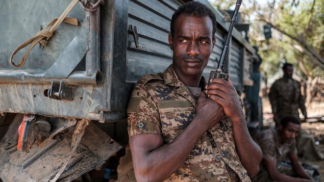 Un soldat éthiopien appuyé sur la boîte d'un camion tient un émetteur-récepteur portatif dans ses mains.