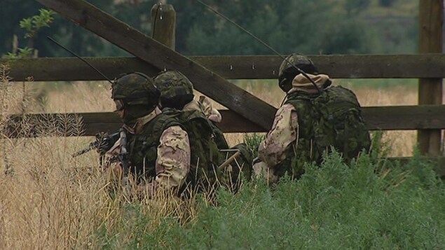 Une équipe de trois soldats de dans un champ près d'une clôture. Une équipe de trois soldats de dans un champ près d'une clôture.