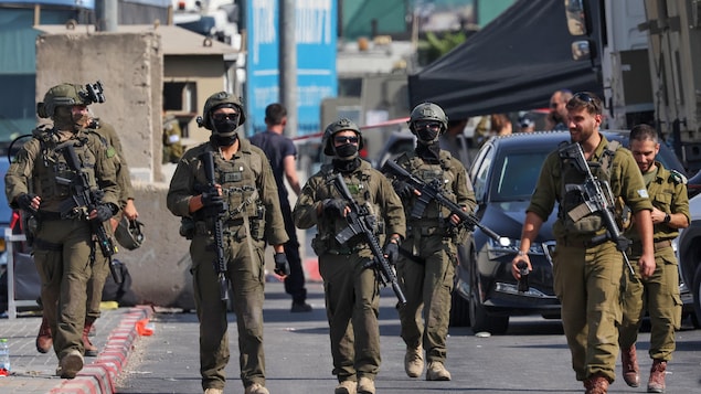 Des soldats israéliens marchent dans une rue.