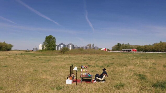 Une personne est assise devant un téléviseur dans le milieu d'un champ