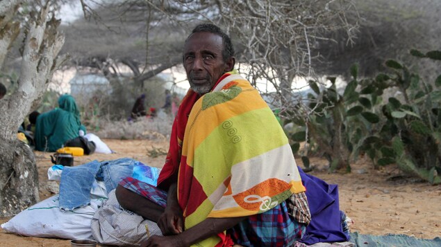 Un homme émacié assis par terre Un homme émacié assis par terre