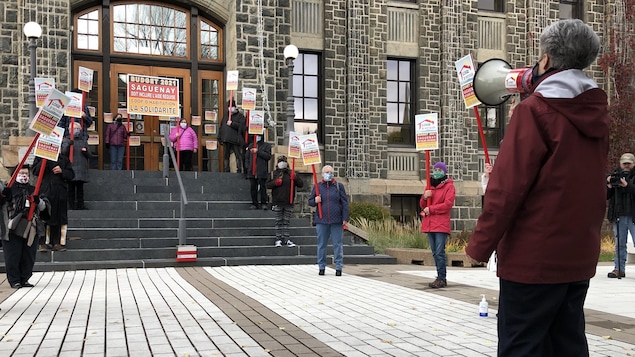Une femme parle dans un porte-voix devant l'hôtel de ville de Saguenay.