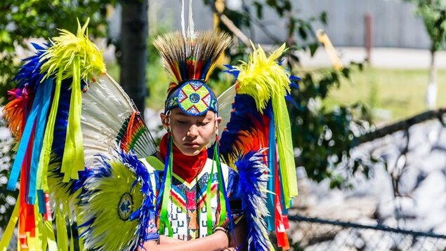 Un jeune autochtone porte les habits traditionnels de la célébration du Powwow Un jeune autochtone porte les habits traditionnels de la célébration du Powwow