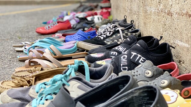Des paires souliers par terre, sur l'asphalte.