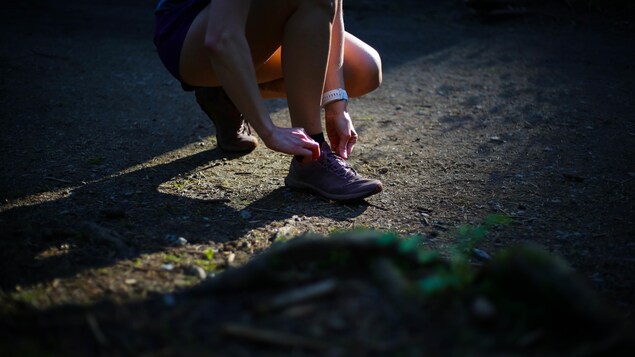 Une personne attache son soulier de course dans un sentier.