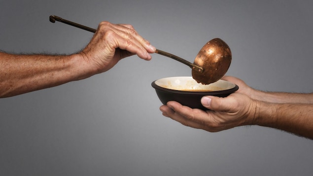 Une main tenant une louche remplie un bol de soupe.