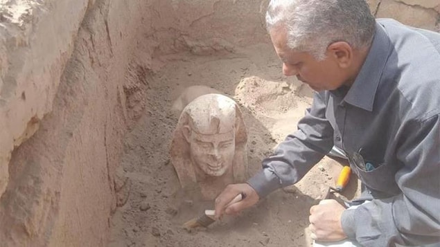 Un archéologue dépoussière une statue.