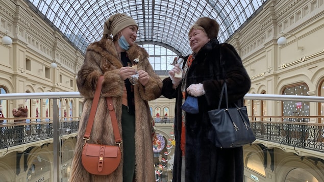 Maria Anikina et une amie sur une passerelle surplombant une place commerciale.